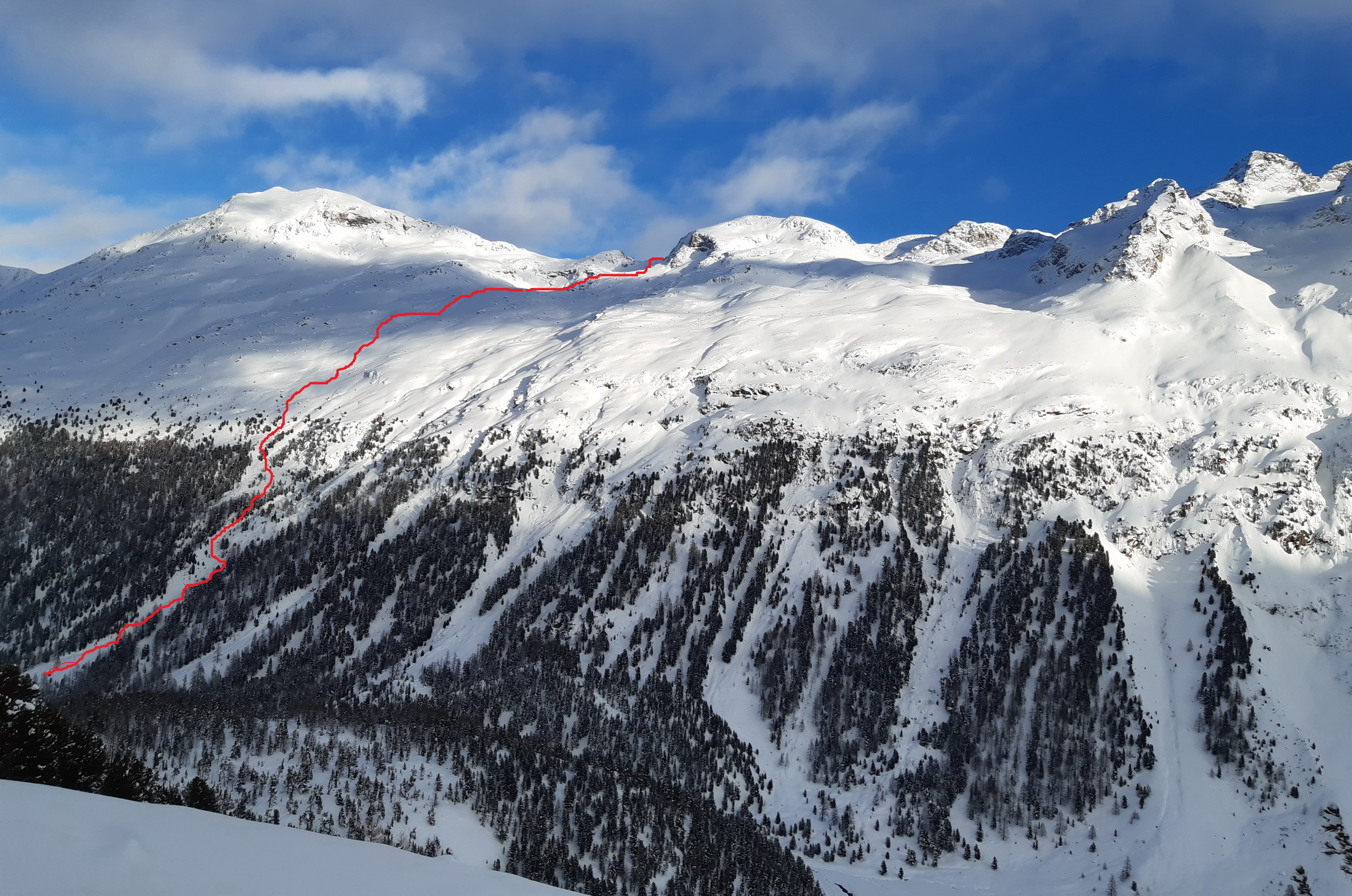 Piz_Mndra_v_strede,_na_vrchol_sa_s_lyžami_stúpa_z_opačnej_strany